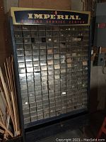 Full view of black metal Imperial shop utility cabinet with almost 200 plastic drawers filled with various small hardware pieces, visible signs of age and use, some rust, some broken drawers.