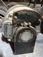 Close-up photo of front of GE electric motor with manufacturer's badge and black mounting plate, showing dust and surface wear.