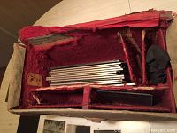 Open vintage photographer's bag showing red velvet lining and metal negative carriers inside.