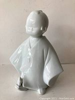 Front angled view of white porcelain kimono figure showing its smooth, glossy finish and minimal detail.