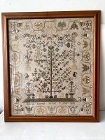 Full front view of framed needlepoint sampler showing entire needlework and wooden frame.