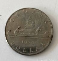 Front view of 1972 Canadian silver dollar coin showing canoe design with two paddlers and year 1972