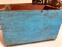 Side view showing blue paint with wear, scratches, and some wood grain visible.