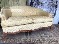 Front view of vintage French style settee showing curved back, patterned beige upholstery, wooden base and legs.