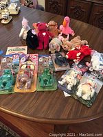 Large collection of Beanie Baby bears and other plush including some in original blister packaging on a wooden table.