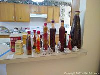 Overview of the lot showing vintage coffee can, baby powder tin, several tall decorative spice/liquid bottles, and various salt and pepper shakers on kitchen counter.