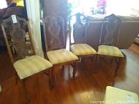 Set of 4 carved wooden dining chairs with upholstered seats, viewed from front