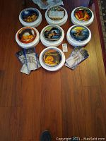 Seven Garfield collector plates arranged on wooden floor, including plate holders