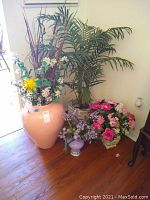 Wide view of four faux plants and flower arrangements in different pots including large pink pot