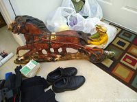 Horse racing wall decor with two jockeys on horses, along with shoes, gloves, and other accessories on floor.