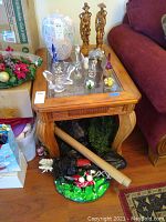 Photo of one wood end table with beveled glass top beside red couch showing side and leg details.