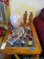 Full lot view showing porcelain vase, resin figurines, art glass swan and bird figures, and multiple glass paperweights on wooden table.