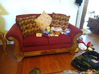 Full front view of burgundy loveseat with decorative pillows and assorted items on cushions