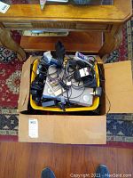 Yellow bin with grey console under tangled controllers and cables