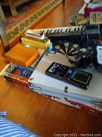 Overview photo showing Yamaha keyboard partially visible, dartboard with colored sections, domino set box, and other boxed games stacked below all items.