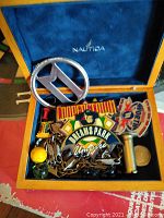 Nautica-lined wooden box filled with assorted keychains and pins including 'Dreams Park' and 'Cooperstown' designs.