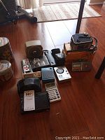 Collection of vintage cameras, camera accessories, and electronics arranged on floor.