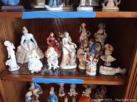 Shelf of figurines including women, children, and decorative busts, some marked Occupied Japan.