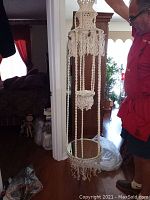 Full view of the macrame hanging shelf suspended, showing the entire length and braided design with tassels.