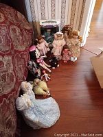 Overall view of the 10 dolls arranged on wood floor showing their size, attire and variety.