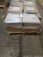 Pallet with multiple cartons of American Olean ceramic floor tiles stacked, several cartons opened showing stacked tiles inside.