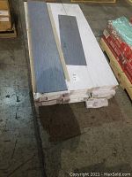 Top stacked view of multiple sealed cartons with vinyl tiles, one box opened showing the tiles and their length and width