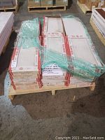 Photo showing multiple stacked boxes of Italian porcelain tile wrapped partially in green plastic on a pallet.