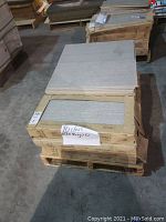 Stack of 10 cartons containing Otto Grigio tiles with two sample tiles placed on top showing size and color