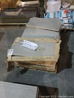 View of stacked cartons containing rectangular Otto Grigio tiles with some damaged packaging and tiles on top.