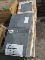 Overview of six boxed Demetra tiles stacked on a pallet with loose grey tiles taped in front