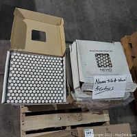 Eight boxes of mosaic tile partially stacked with one box open showing white round penny tiles.