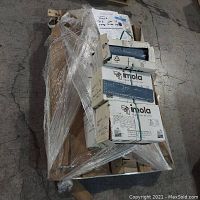 Eight cartons of Imola ceramic wall tiles stacked on a wooden pallet wrapped in clear stretch plastic film, showing packaging and tile boxes intact.