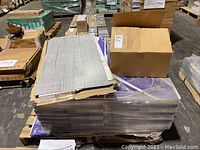 Pallet of stacked purple boxes with loose grey vinyl tiles on top