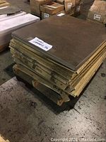 Stack of 15 boxes of brown stone-like tiles measuring 29.5 x 29.5 cm on a pallet in warehouse setting.