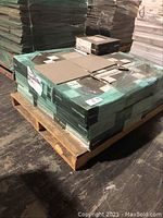 Pallet stacked with multiple boxes of Durastone porcelain tiles, wrapped in green packaging with brand name visible