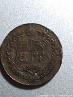 Photo of the medal's side with the Canadian coat of arms, surrounded by a laurel wreath and crown above.