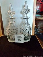 Pair of Victorian glass decanters with glass stoppers inserted, shown upright on a dark surface.