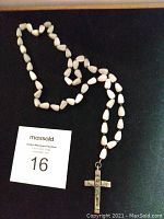 Photo showing the full length of the necklace with white mother of pearl beads and metal cross pendant.