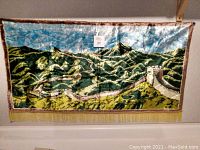 Full view of the silk wall hanging depicting the Great Wall of China with fringe border and landscape details.