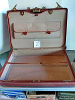 Open suitcase showing beige fabric lining and internal compartments including zippered section and button snap pocket