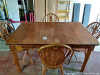 Pine dining table with four chairs placed around it, showing overall set and style.