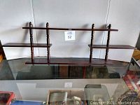 Photo showing both walnut display shelves placed on a glass surface against a wall, highlighting the overall shape and size.