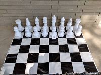 White plastic chess pieces arranged on black and white vinyl chess mat