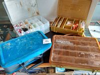 Photo showing three fishing tackle boxes: clear plastic, yellow Magnum, and blue carrying case on a wooden surface.