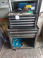 Full view of two stacked metal tool chests with some hand tools visible on top and inside drawers.