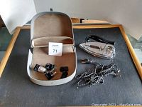 Photo of the vintage travel iron with carrying case and accessories laid out on a table.