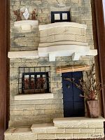 Close-up of the textured 3D depiction of the villa showing balcony, windows, door, and plants in natural tones.