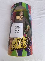 Front view of the sealed cylindrical packaging showing Dr Evil doll holding Mr Bigglesworth cat with sticker and colorful Austin Powers branding