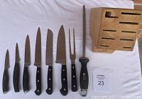 Full layout of all 6 knives, meat fork, sharpening steel, and knife block on white surface