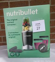 Front view of Nutribullet box showing the main product and accessories inside, emphasizing 600 watt motor and 12 piece set.